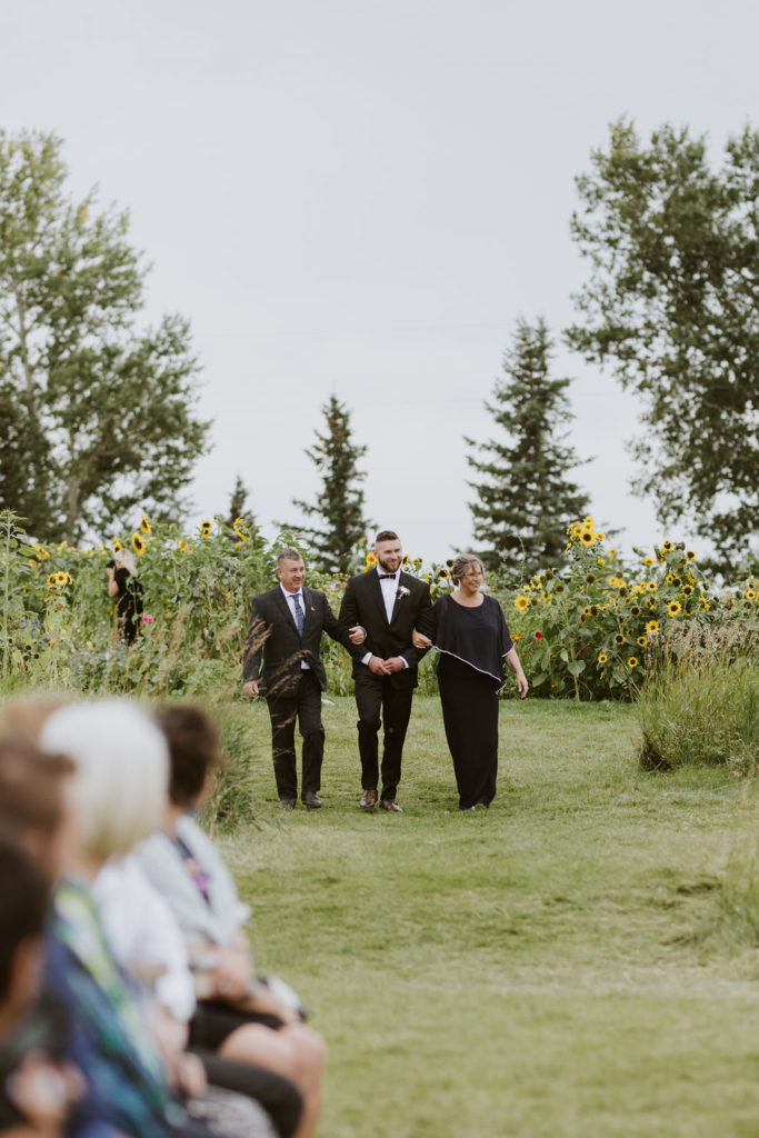 groom walking down the aisle with his parents - outdoor garden weddings