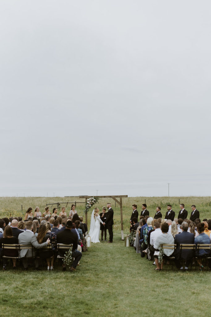 field ceremony space with couple surrounded by family and friends