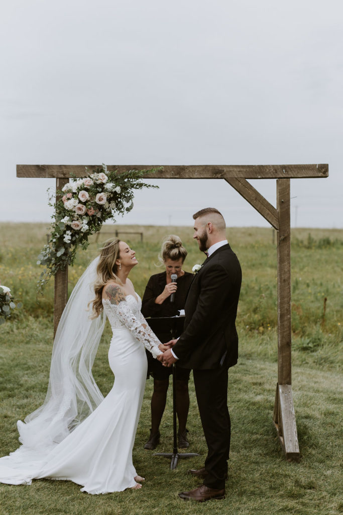 outdoor wedding ceremony with decorated arch, located in a field