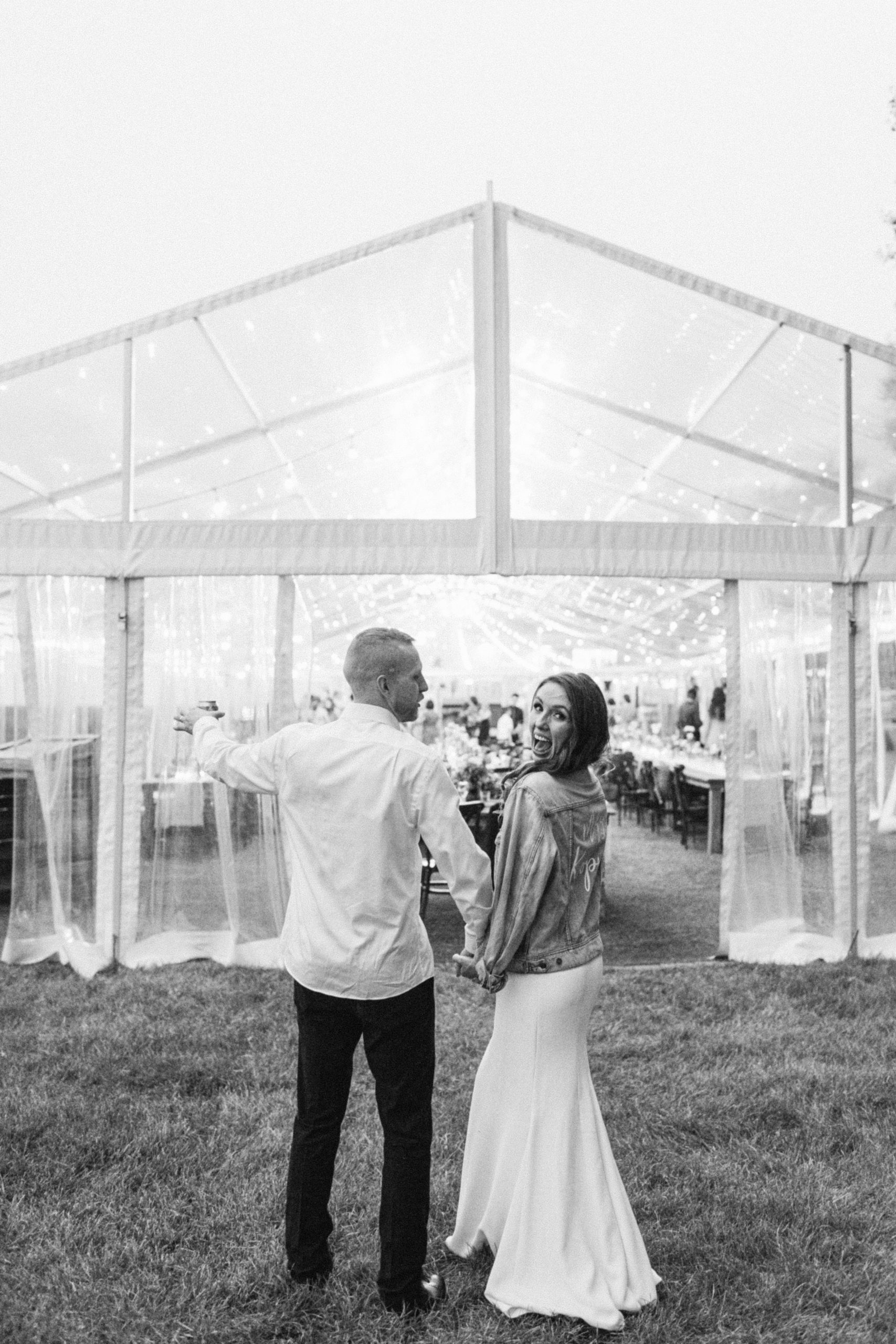 A bride and groom standing in front of a tent, ready to embark on a reception to remember.