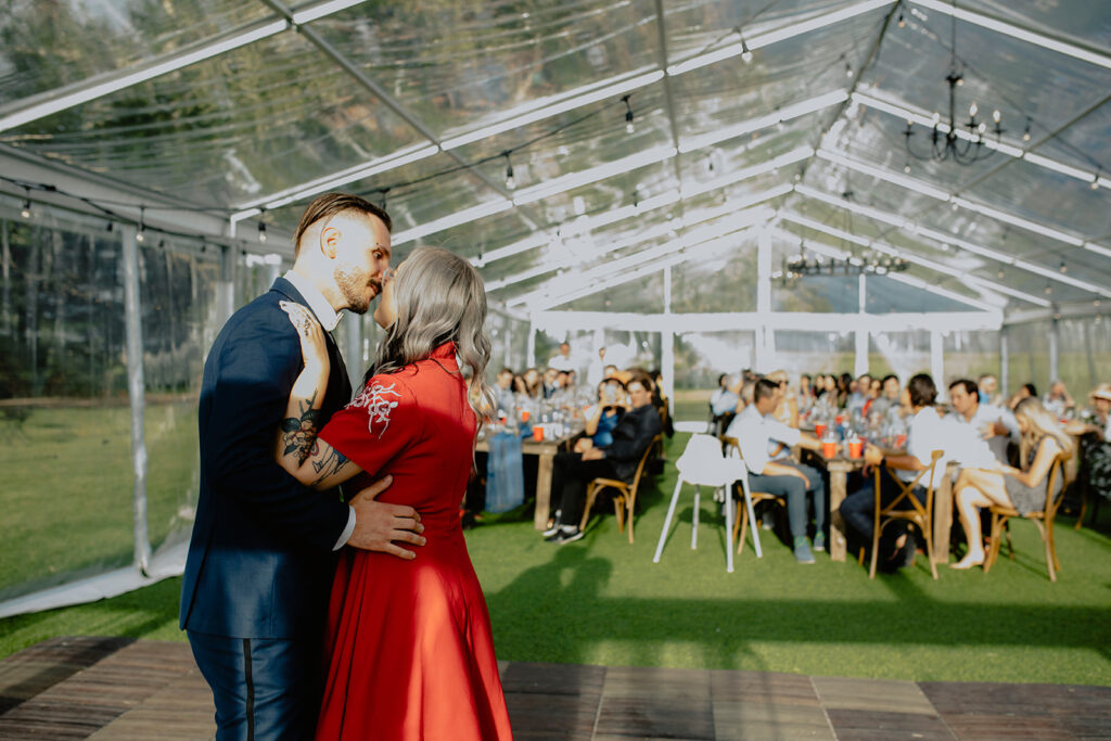 A bride and groom sharing their first dance under a tent.