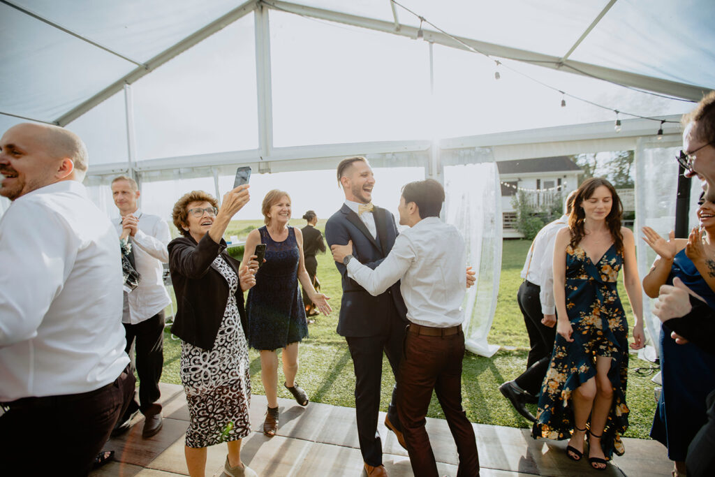 A group of people dancing in a tent at a wedding.
