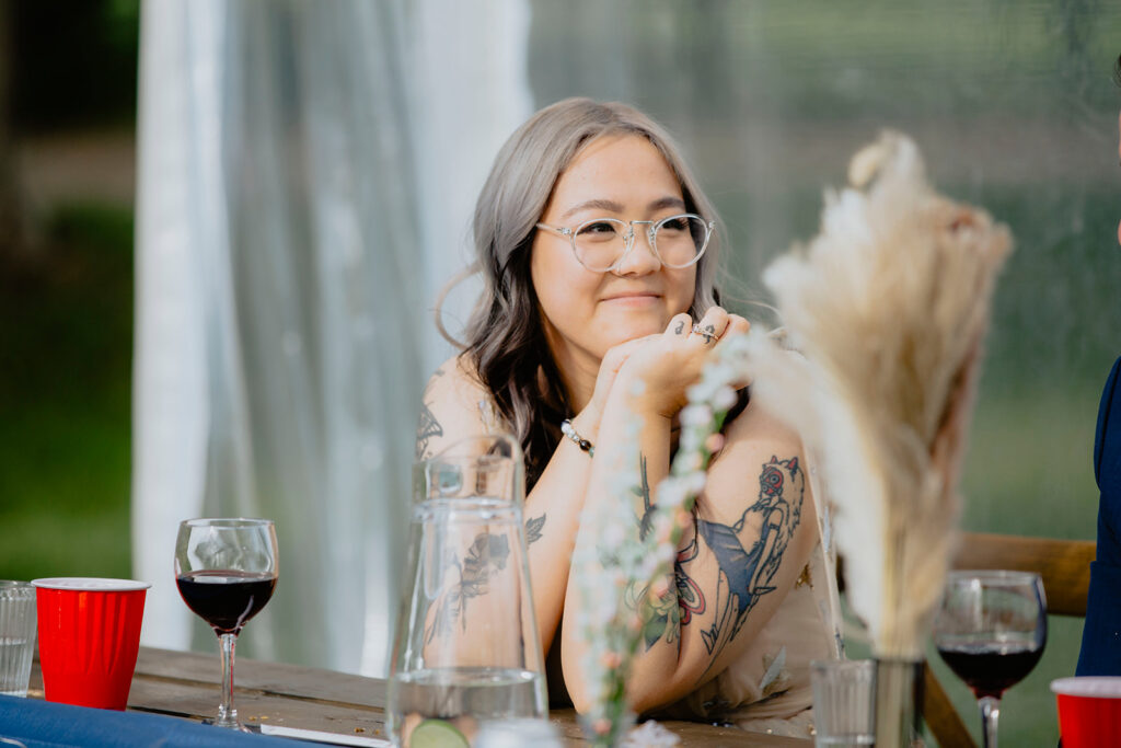 A bride with tattoos sitting at a table.