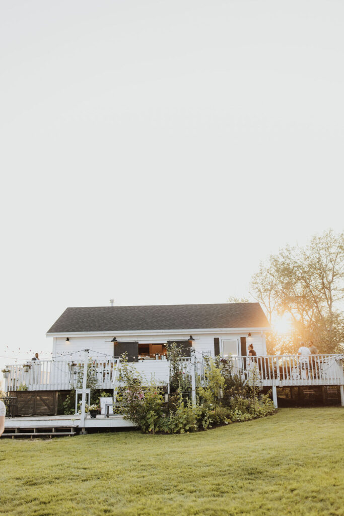 A bride and groom standing in front of a house at sunset.