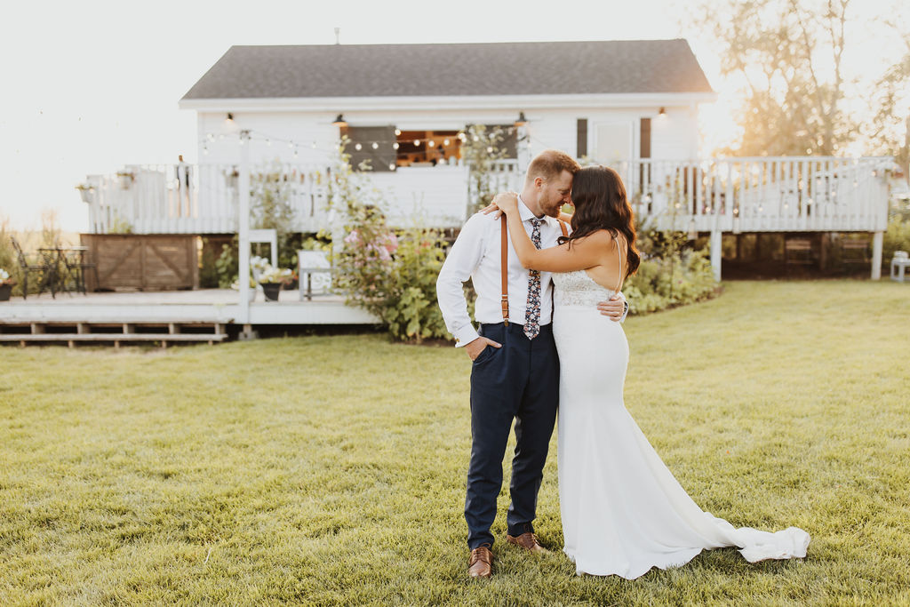 A bride and groom embracing in front of a house at sunset. Enchanting Outdoor Dinner Party.