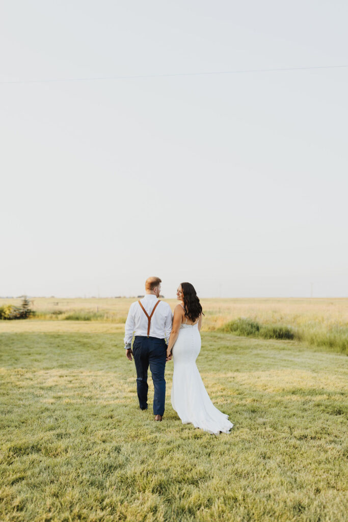 A bride and groom walking through a grassy field.Enchanting Outdoor Dinner Party