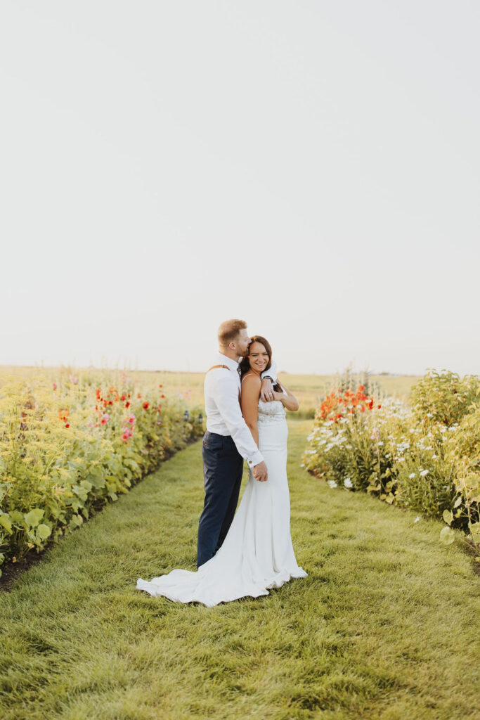 A bride and groom standing in a field of flowers. Garden party wedding at the Gathered