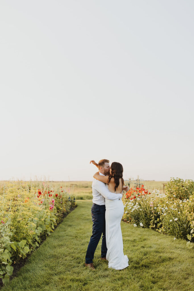 A bride and groom embrace in a flower garden at The Gathered outdoor wedding and events venue.