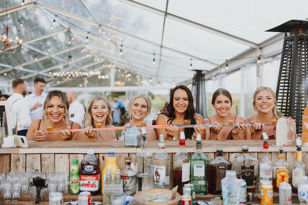 A group of bridesmaids standing behind a bar.