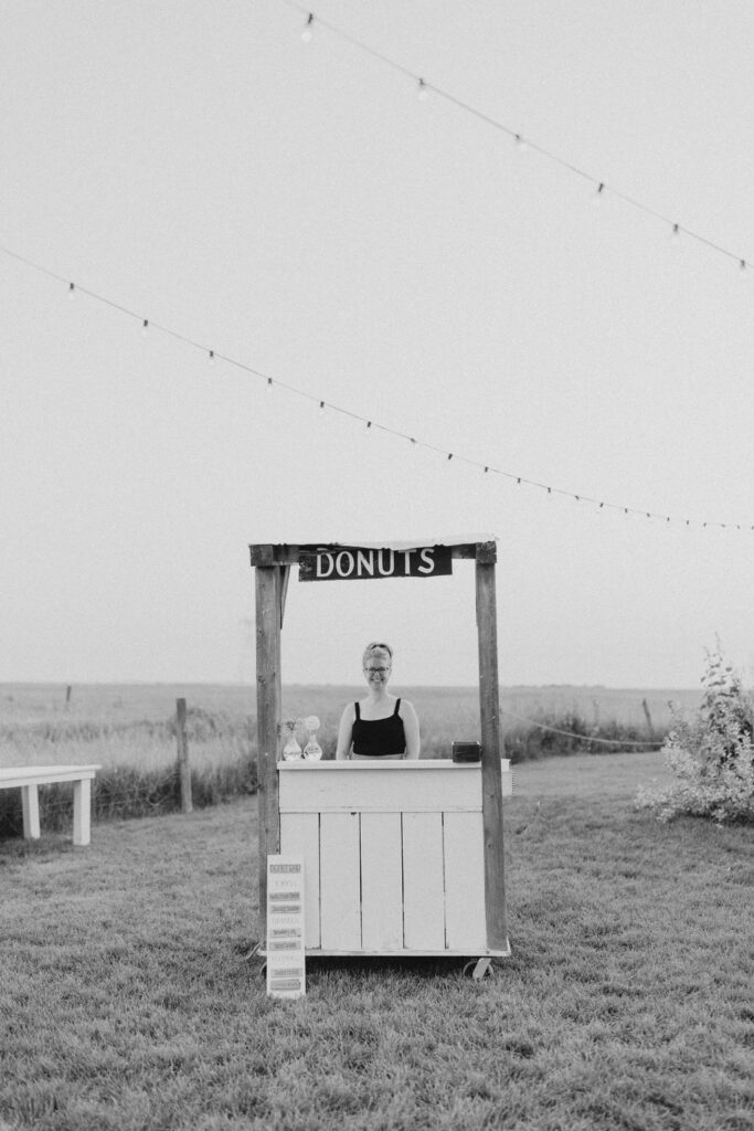 A woman standing in front of a donut cart.