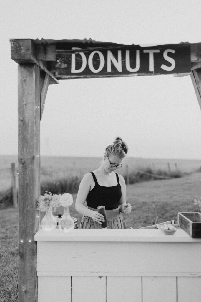 A woman standing in front of a donut stand.