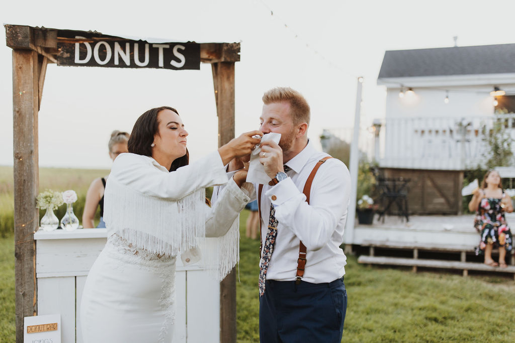 A bride and groom feeding donuts to each other.