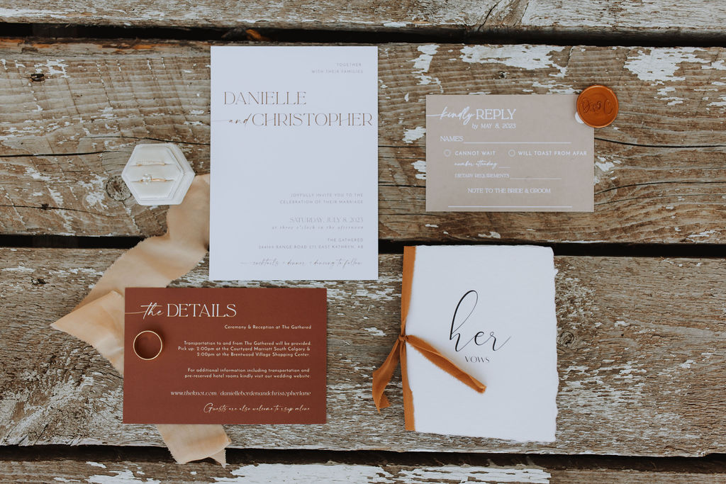 A wedding invitation set on a wooden table.