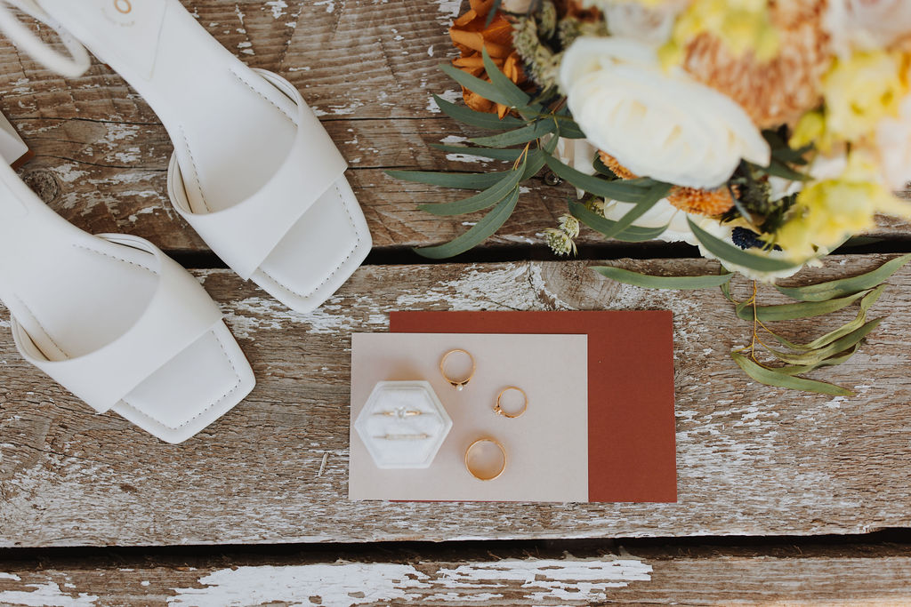 A pair of white shoes and a wedding card on a wooden table.