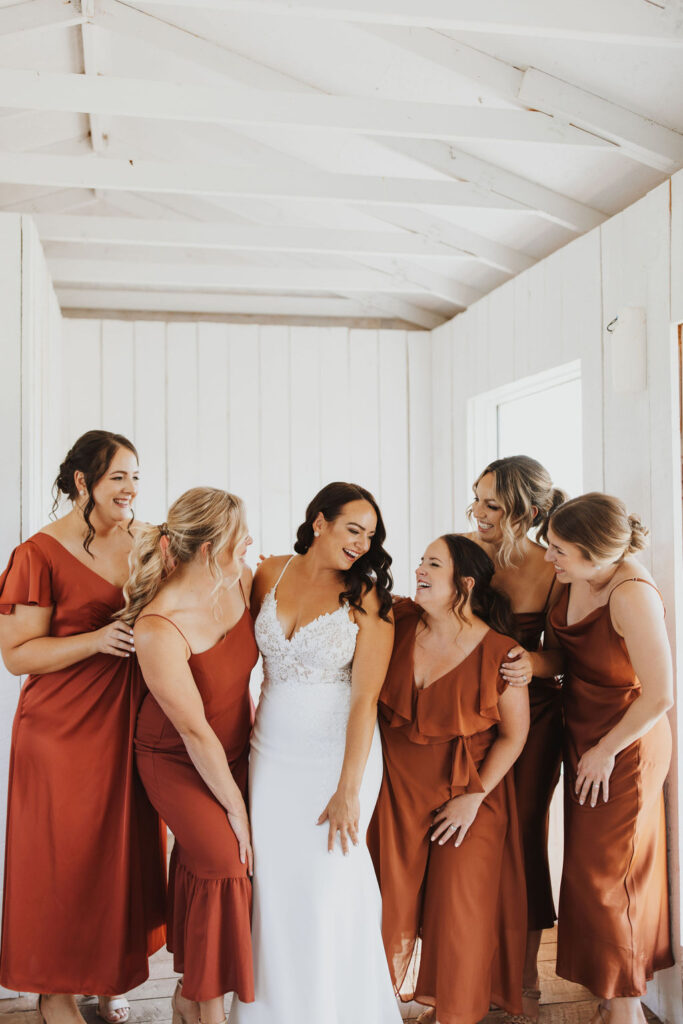 A bride and her bridesmaids in orange dresses.