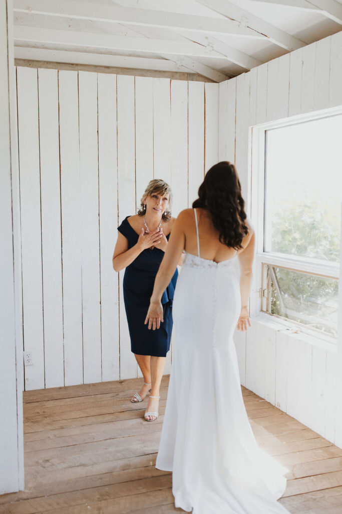 A bride and her mother are getting ready in a room.