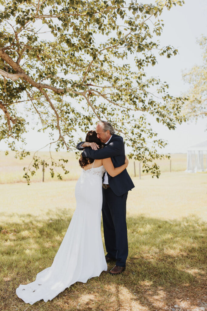 A bride and groom hugging under a tree.