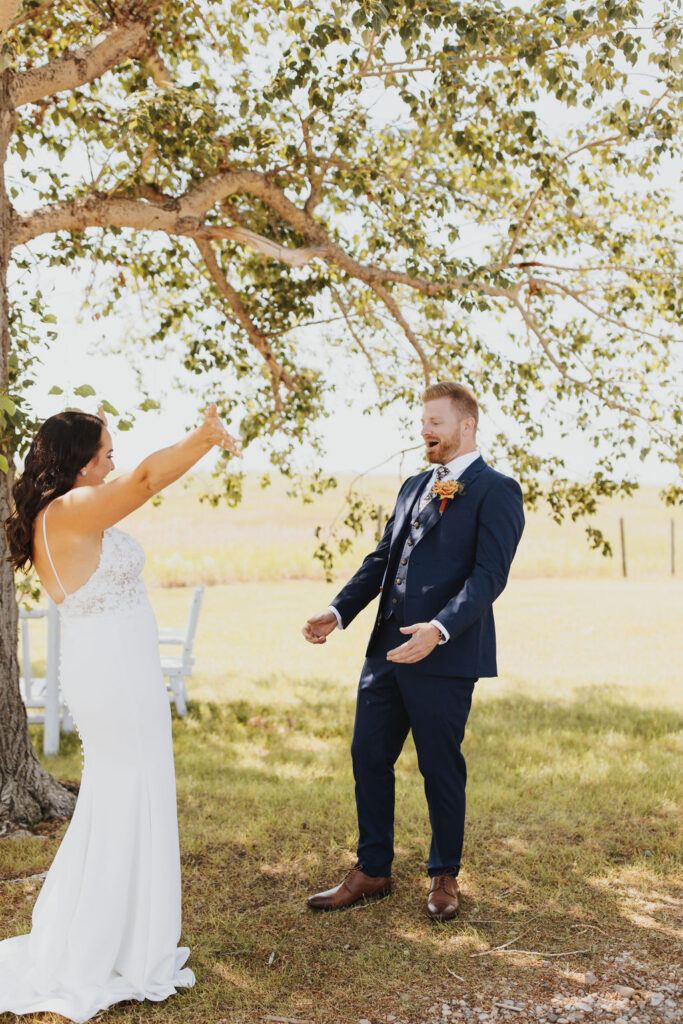 A bride and groom throwing their hands in the air in front of a tree.