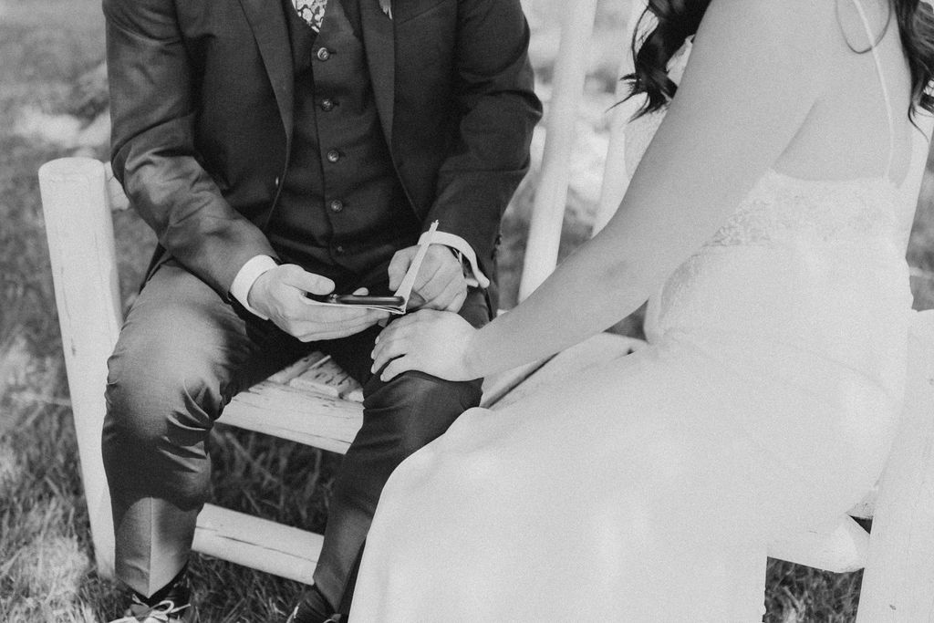 A bride and groom sitting in a chair.