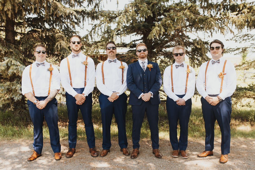 A group of groomsmen standing in front of a tree.