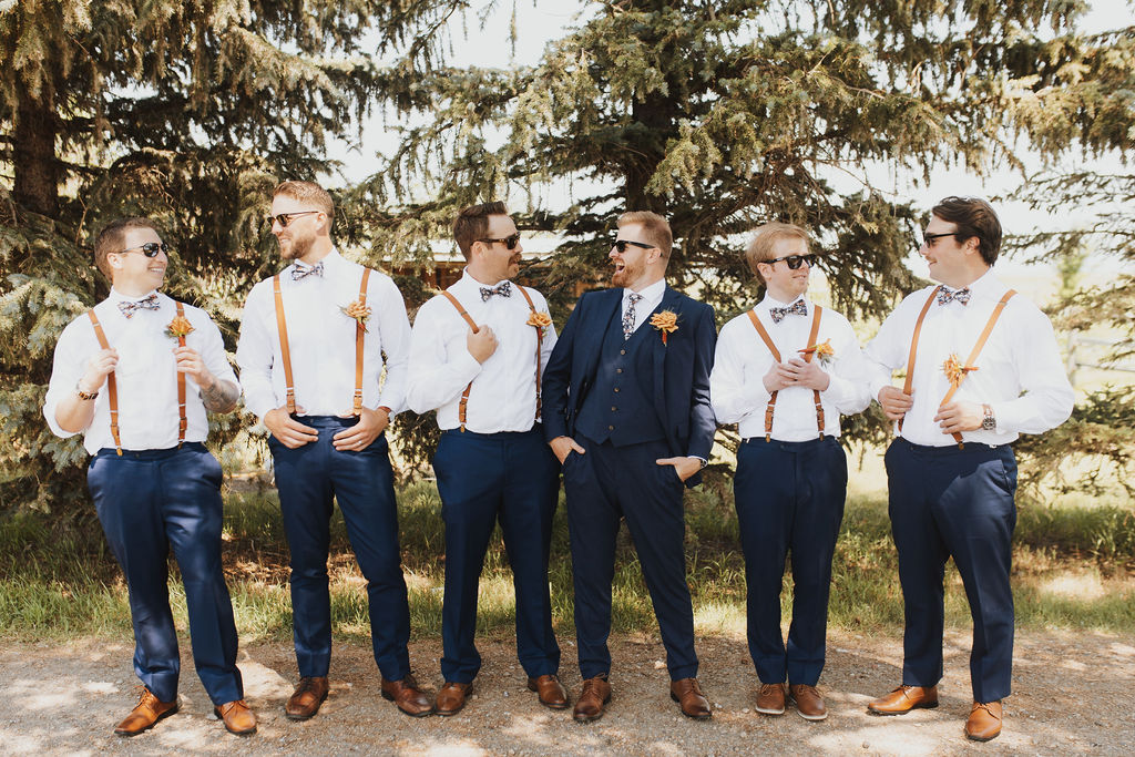 A group of groomsmen wearing suspenders and ties.