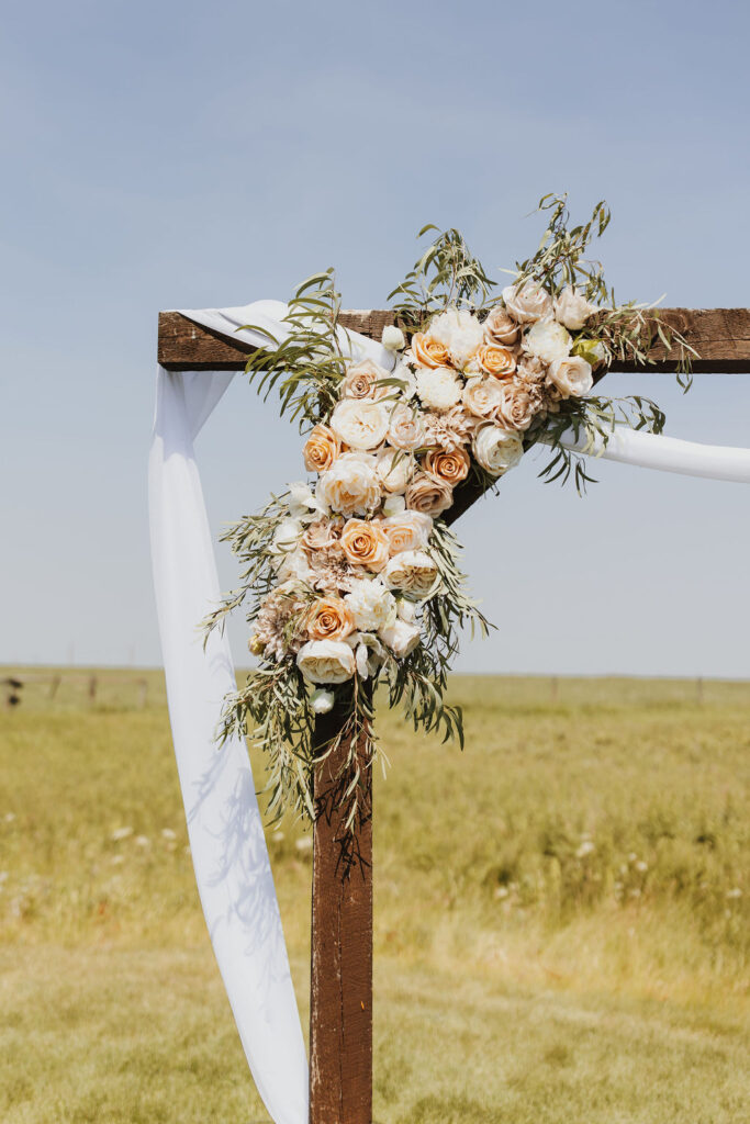 A wedding arch decorated with flowers in the middle of a field.