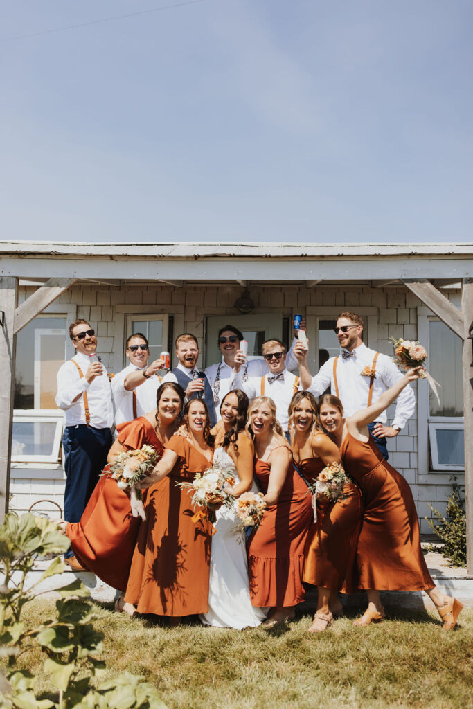 A group of bridesmaids in orange dresses pose for a photo. Outdoor Dinner Party