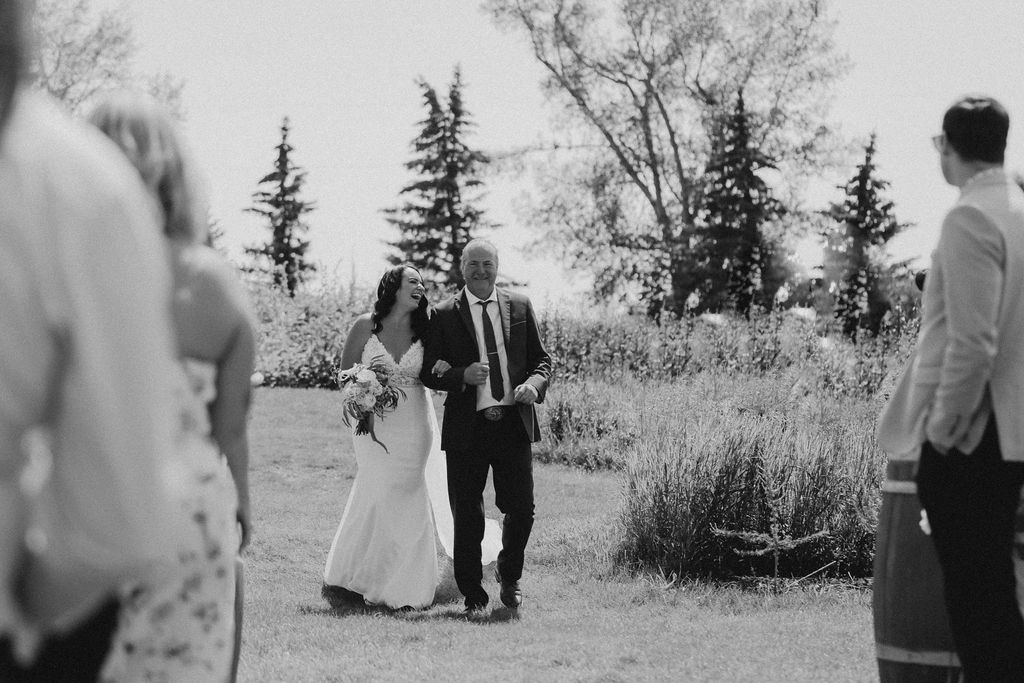 A black and white photo of a bride and groom walking down the aisle.