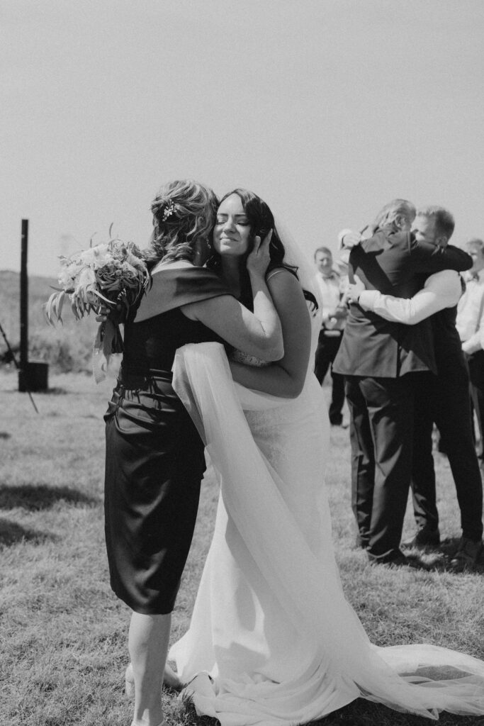 A bride is hugging her bridesmaid at a wedding.