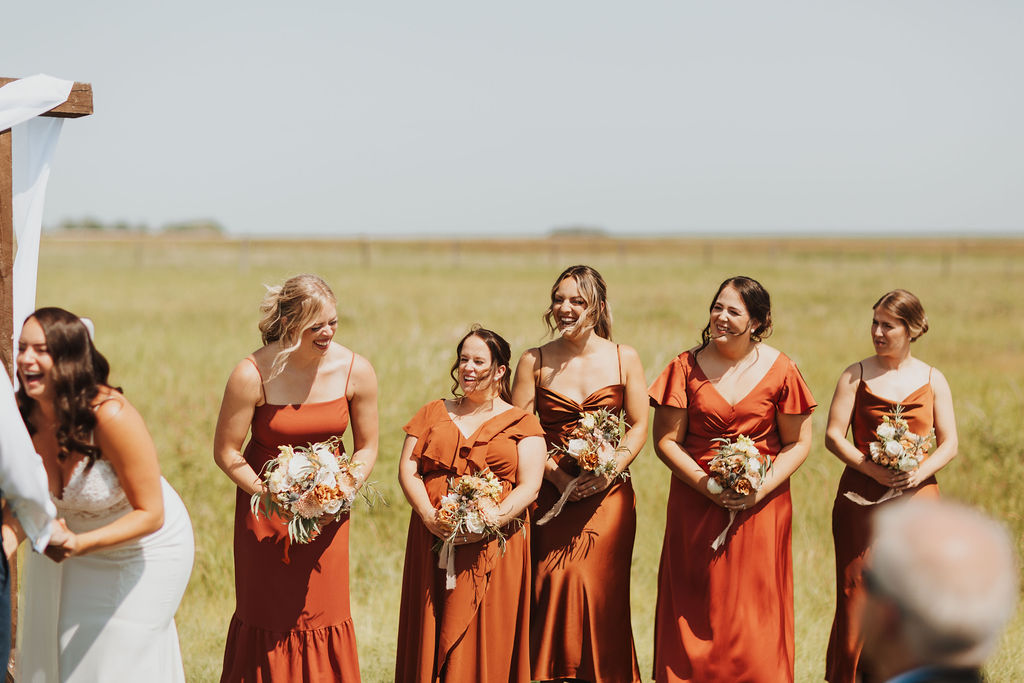 A group of bridesmaids in orange dresses at a wedding ceremony.