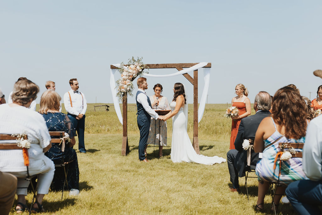 A bride and groom exchange vows in the middle of a field.