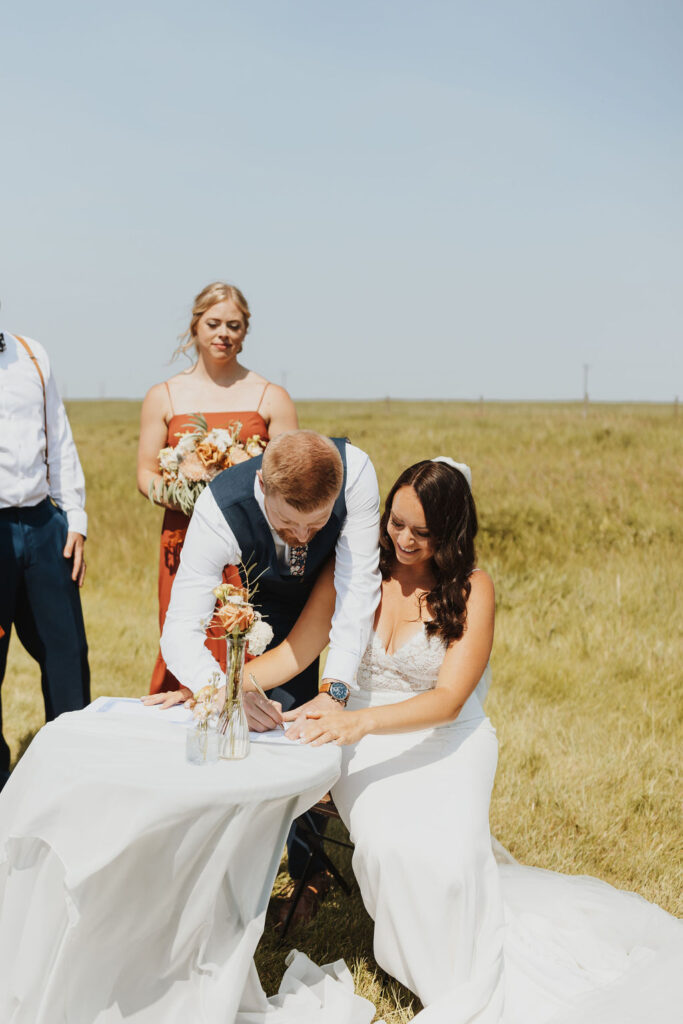 A bride and groom signing their wedding vows in a field.