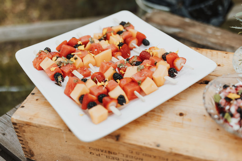 A plate of fruit skewers on a wooden table.