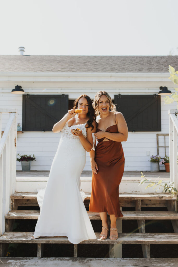 Two bridesmaids standing on the steps of a house.