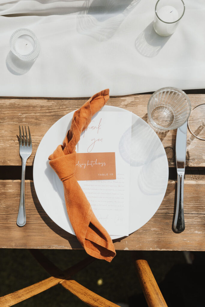 A plate with napkin and silverware on a wooden table. Outdoor Dinner Party