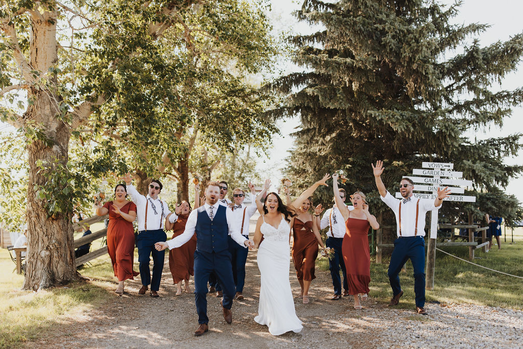 A group of bridesmaids and groomsmen walking down a path.