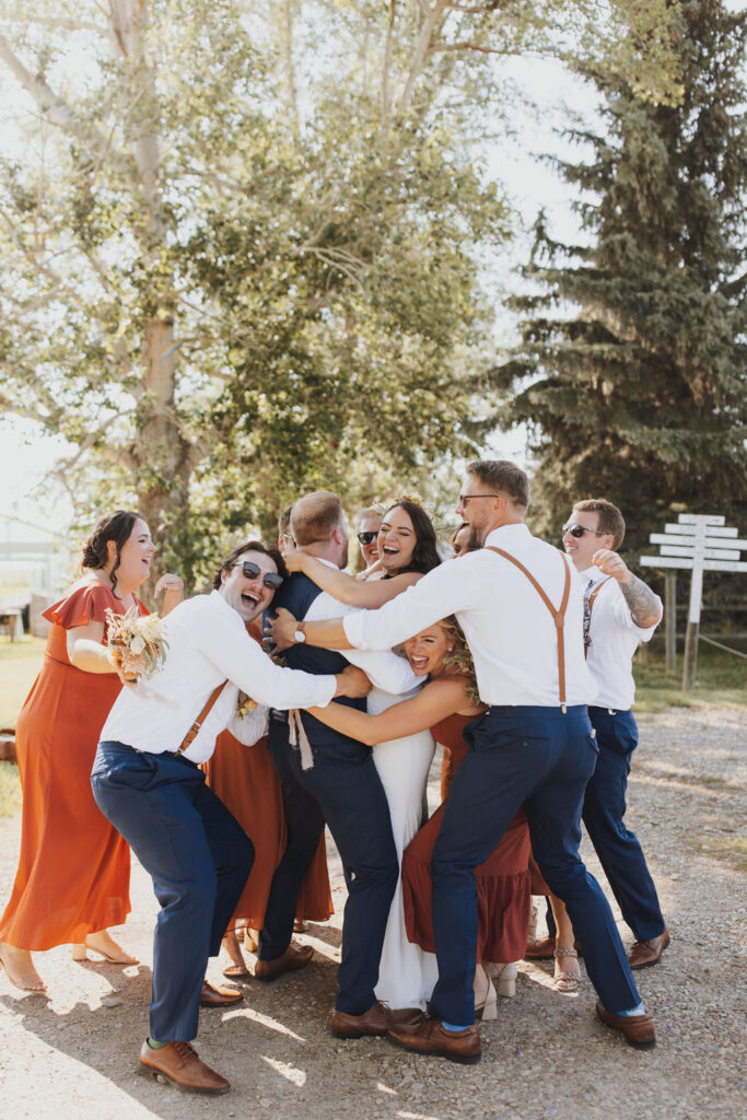 A group of bridesmaids hugging on a dirt road.