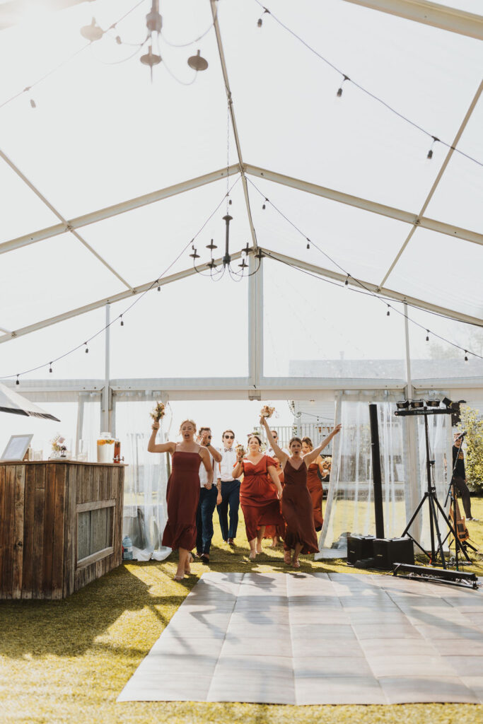 A group of bridesmaids dancing in a tent.