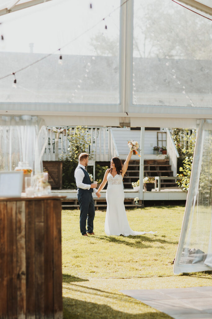 A bride and groom standing in front of a tent.