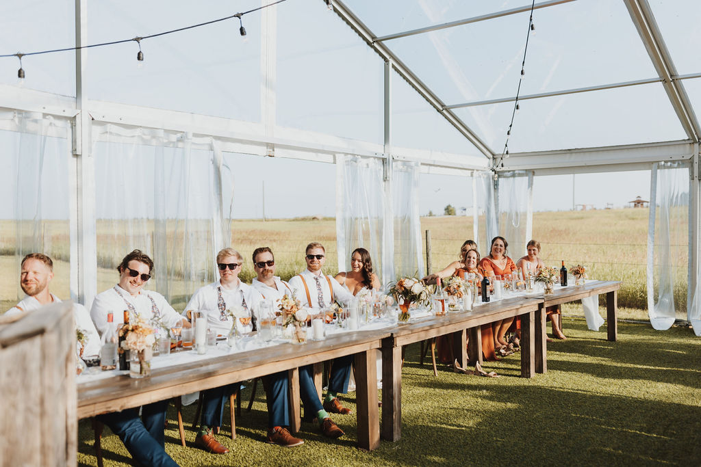 A group of people sitting at a long table in a tent.