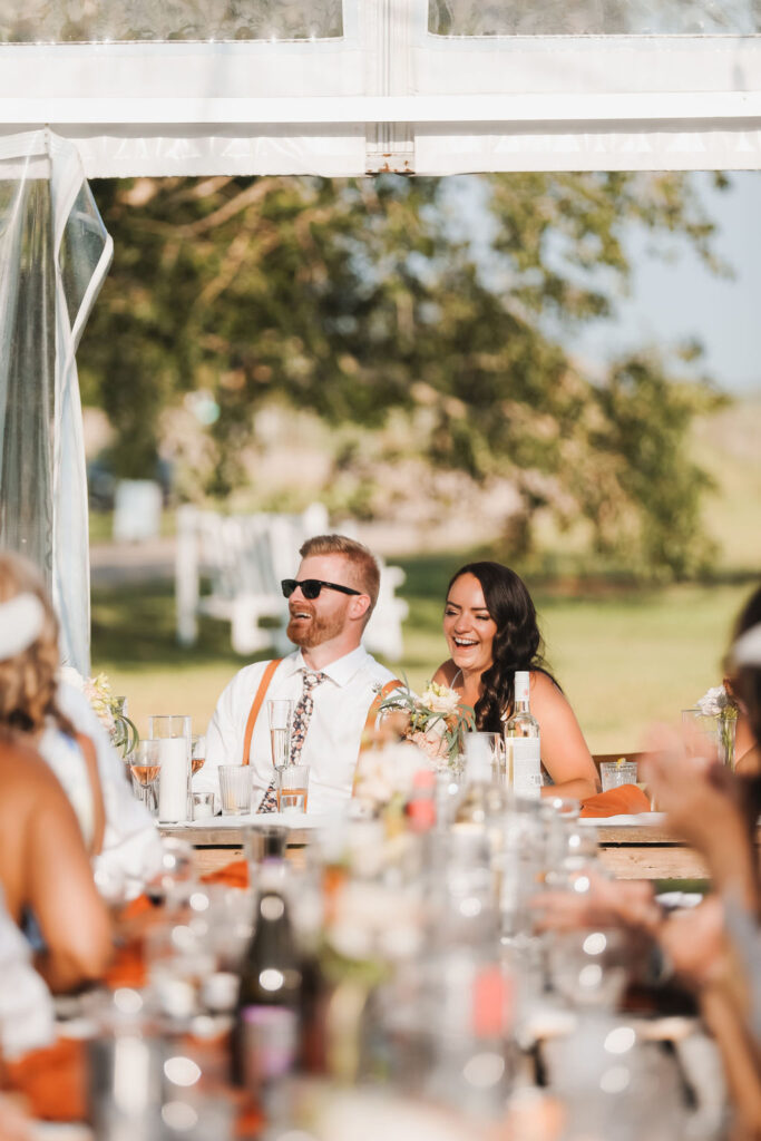 A group of people sitting at a table at an outdoor wedding.