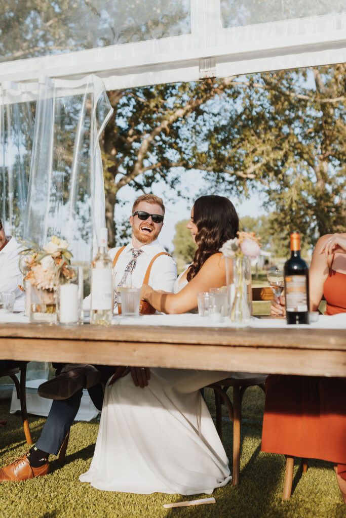 A group of people sitting around a table at a wedding.