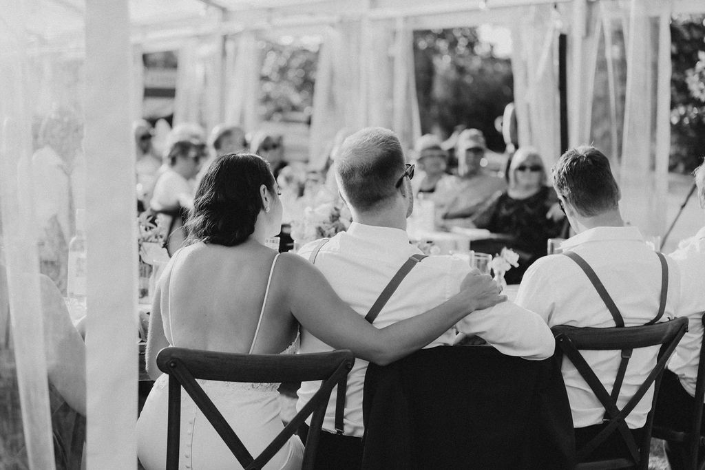 A bride and groom sitting at a table at a wedding.