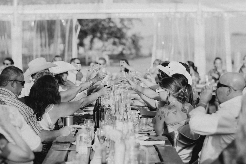 A black and white photo of a group of people toasting at a table.