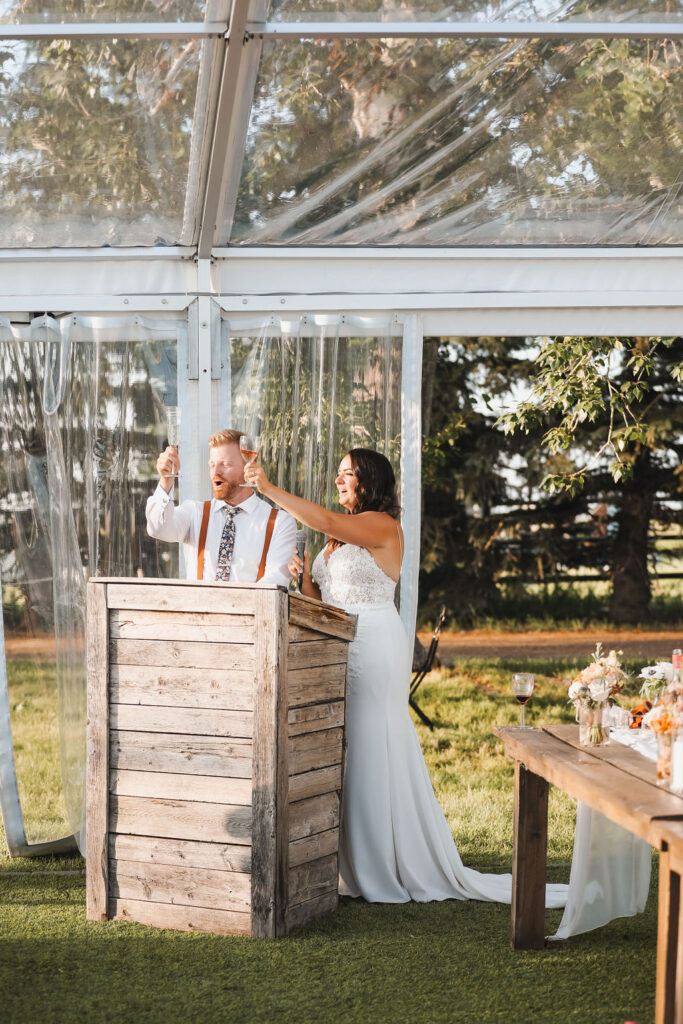 A bride and groom giving a toast in a tent.