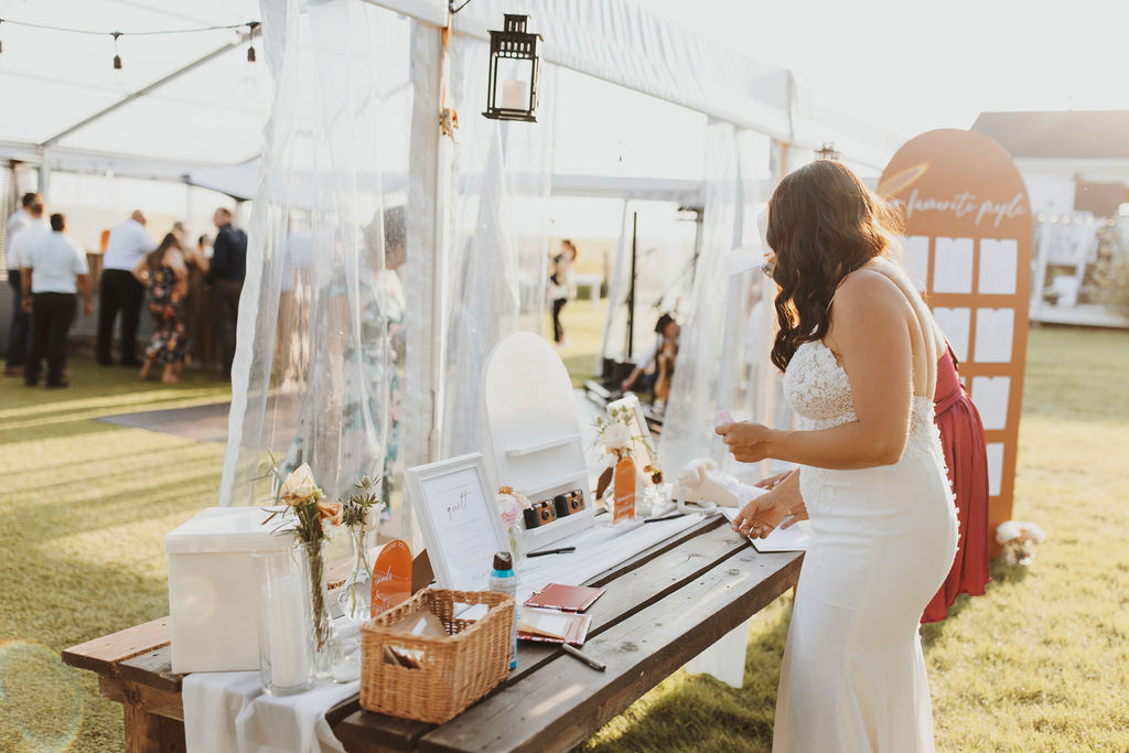 A bride standing at a table at an outdoor wedding.