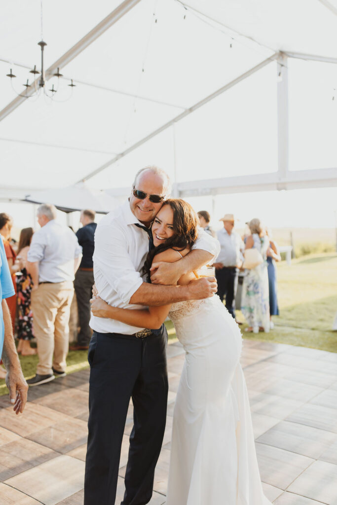 A bride and groom hugging in front of a tent. Enchanting Outdoor Dinner Party
