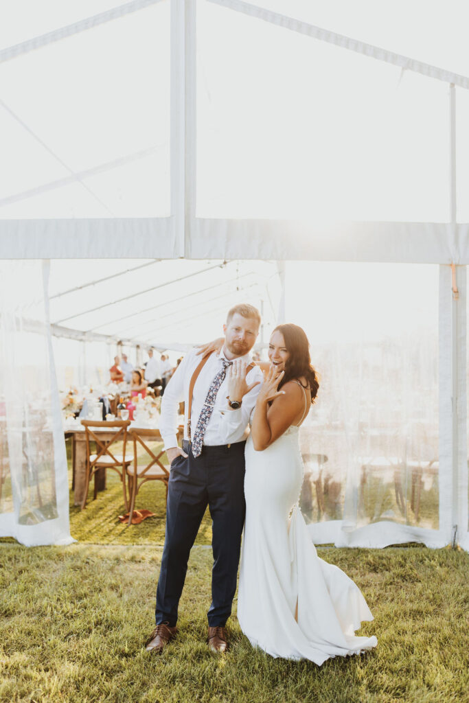 A bride and groom standing in front of a tent.