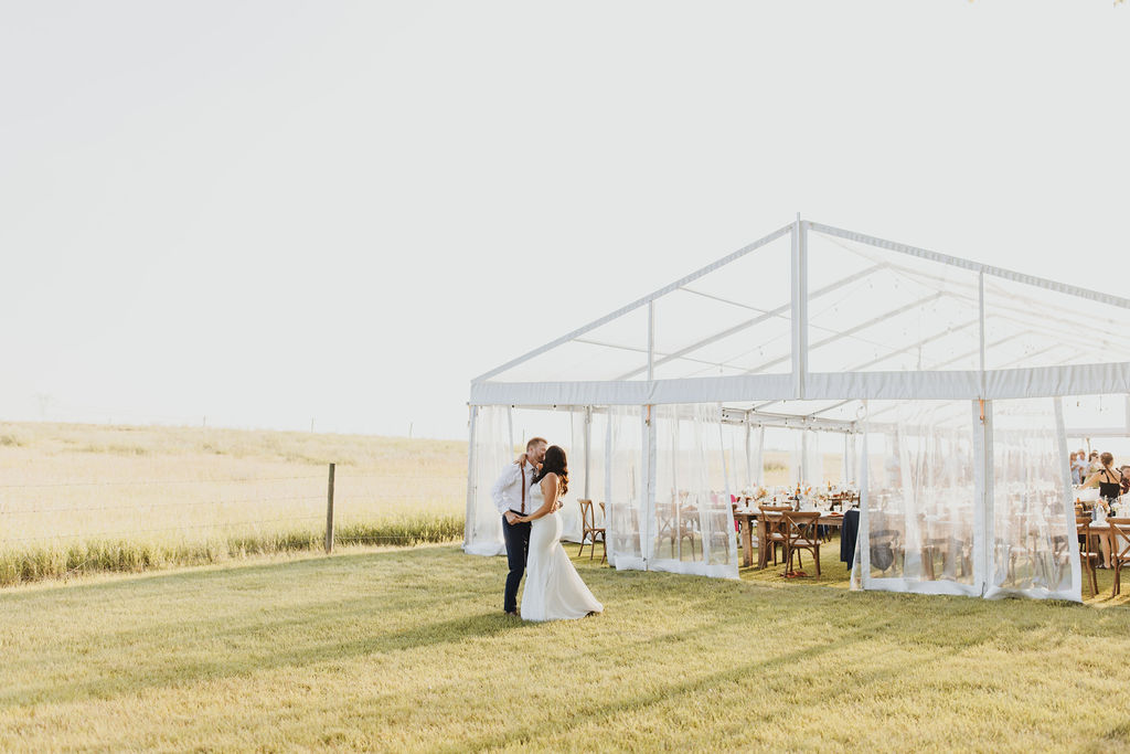 A bride and groom kidding in front of a clear outdoor wedding tent. Enchanting Outdoor Dinner Party