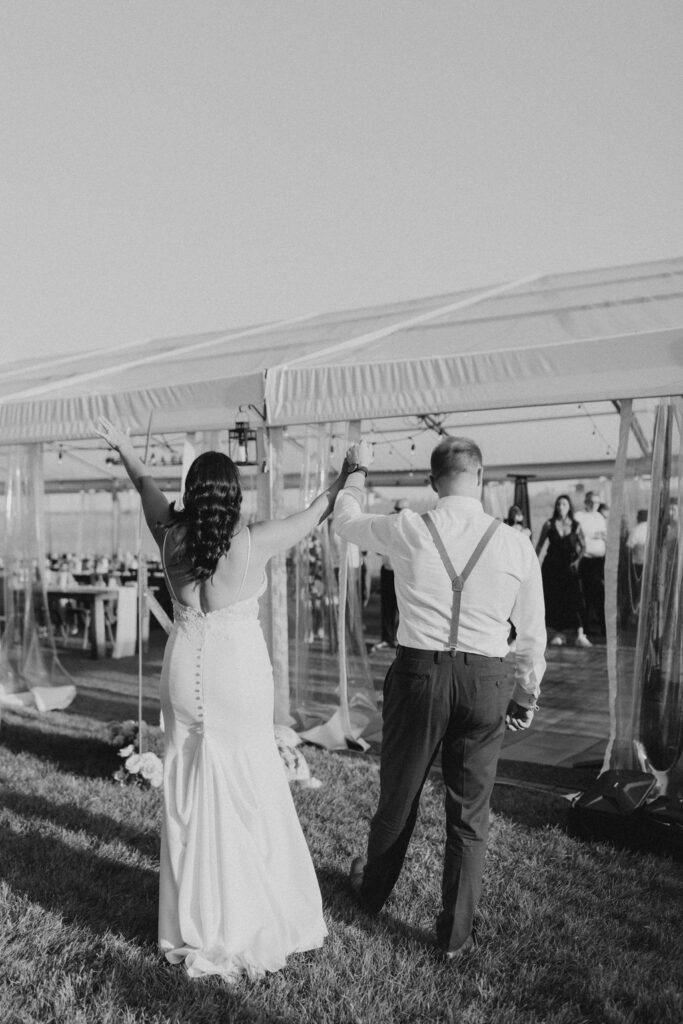 A bride and groom holding hands in front of a tent.